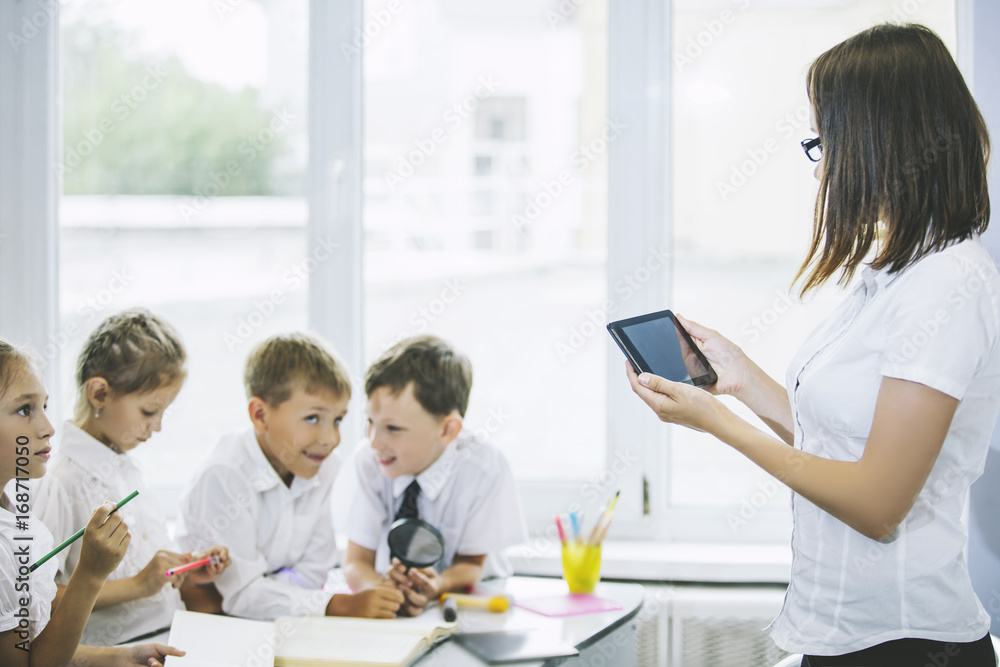 Beautiful children, the students and teacher together in a classroom at the school receive education with tablets happy Beautiful children, the students and teacher together in a classroom at the school receive education with tablets happy