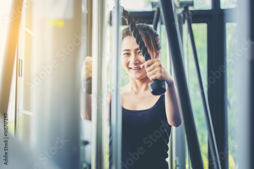 pretty woman exercise with cable weight machine in gym.