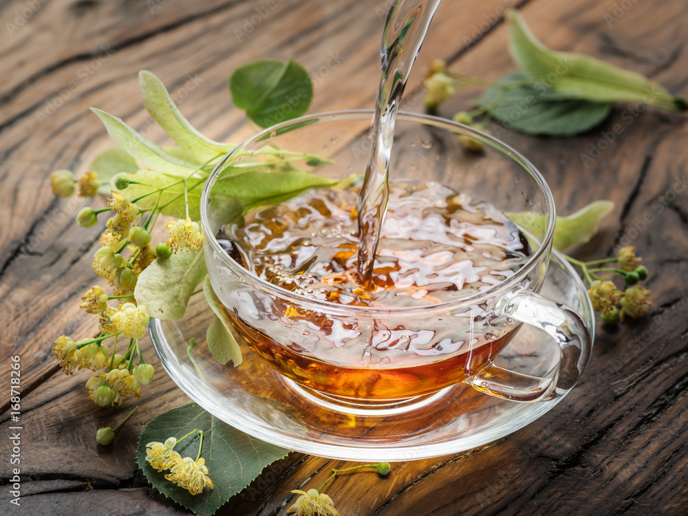 Cup of linden tea and lime flowers on the wooden table. Cup of linden tea and lime flowers on the wooden table.