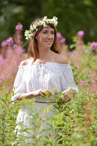 Brunette in white in summer tea willow field with wreath on head photo