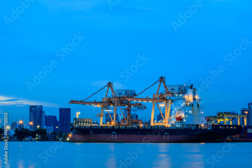 Container loading by crane, cargo ship at shipping port at twilight, Logistics and transportation concept