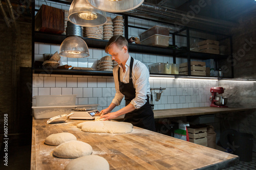 baker portioning dough with bench cutter at bakery photo