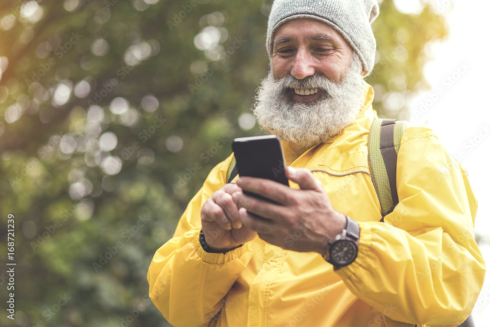 Joyful old man using mobile phone in woodland Joyful old man using mobile phone in woodland