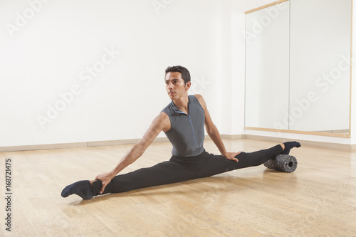 professional ballet dancer stretching and warming up using foam roller