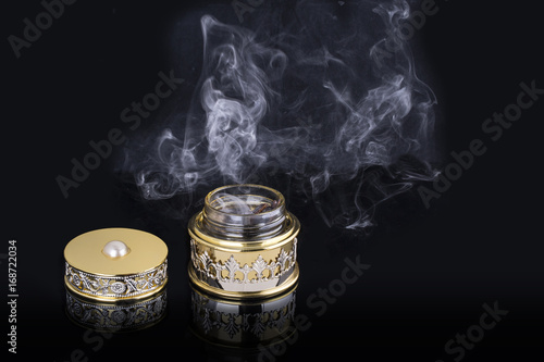 Quadro su tela Incense of Traditional Arabian Fragrance Oudh Bakhoor in a maroon glass jar on l