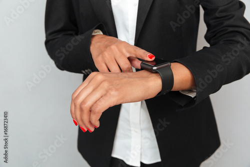 Business woman over grey wall using watch.