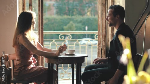 Young man and woman drinking coffee in a loft cafe. Kiss on a romantic date