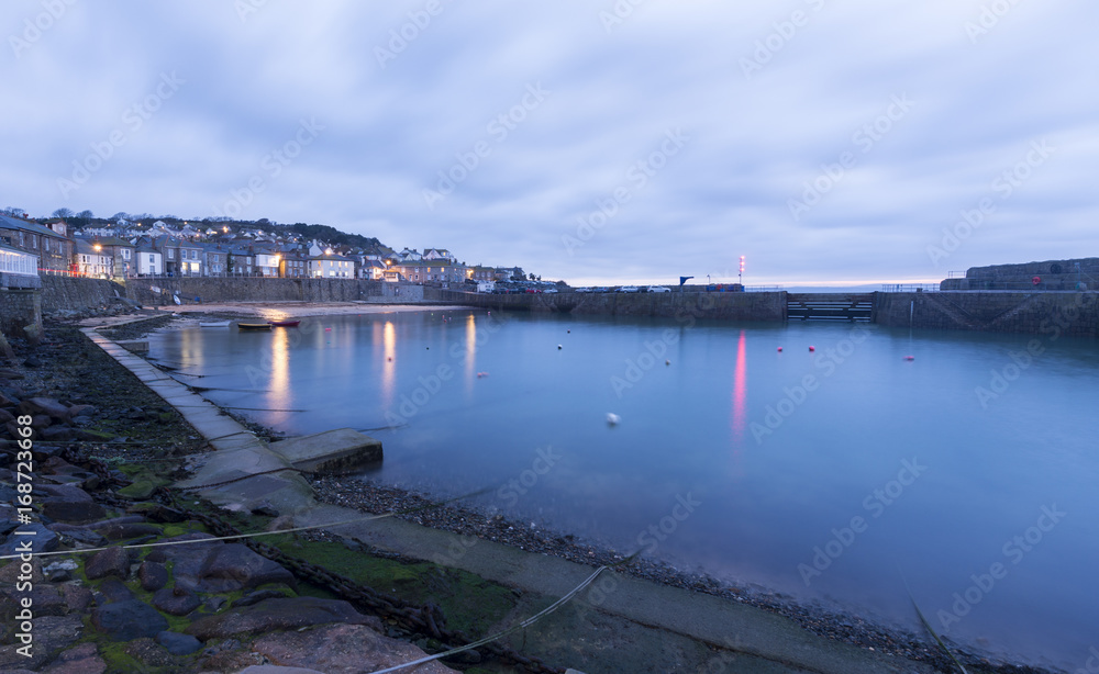 Mousehole Harbour in Cornwall at sunrise.