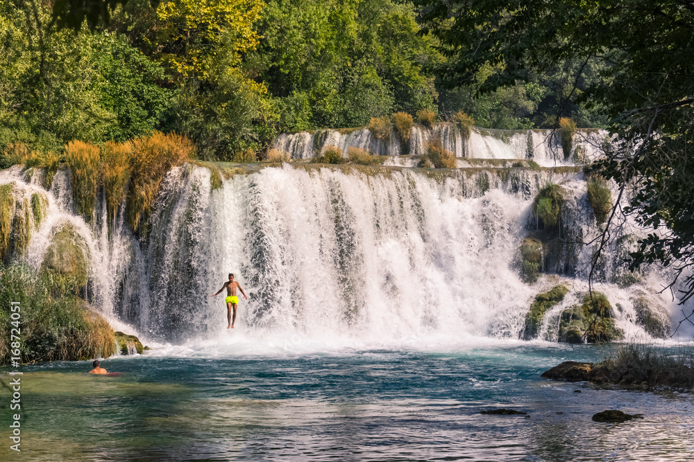 Fototapeta premium Boy Jumping in the Krka Falls During Summer Vacation August 2017