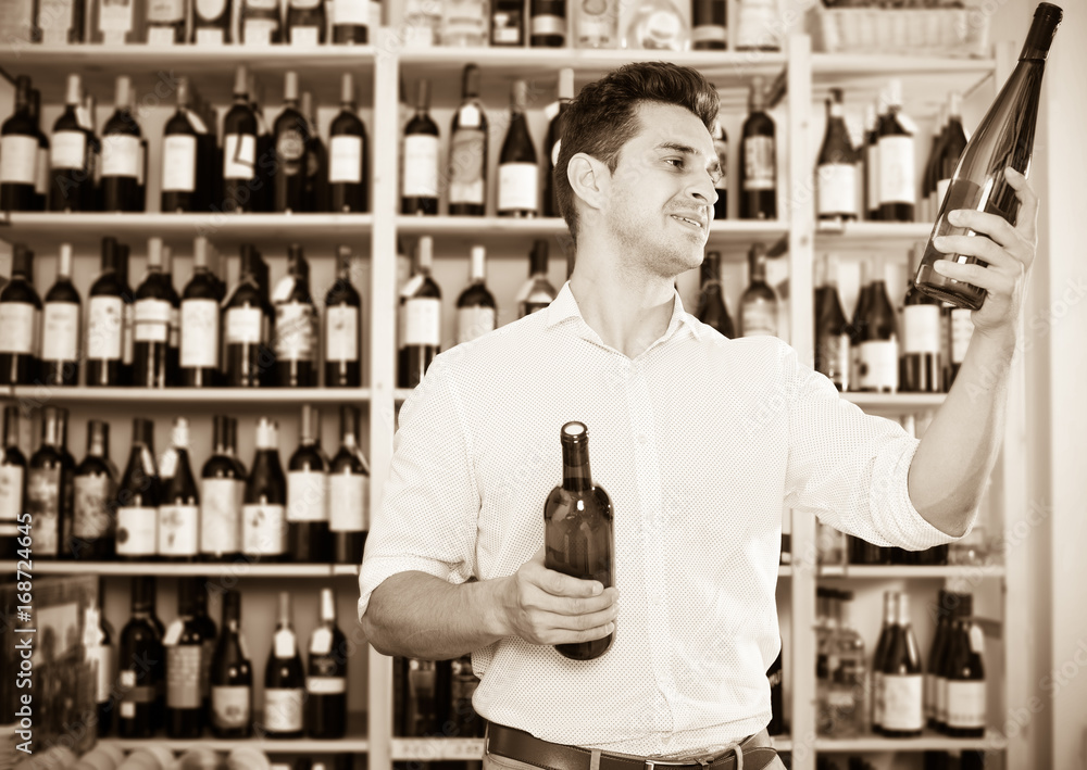 Man expert holding wine bottles in winery section