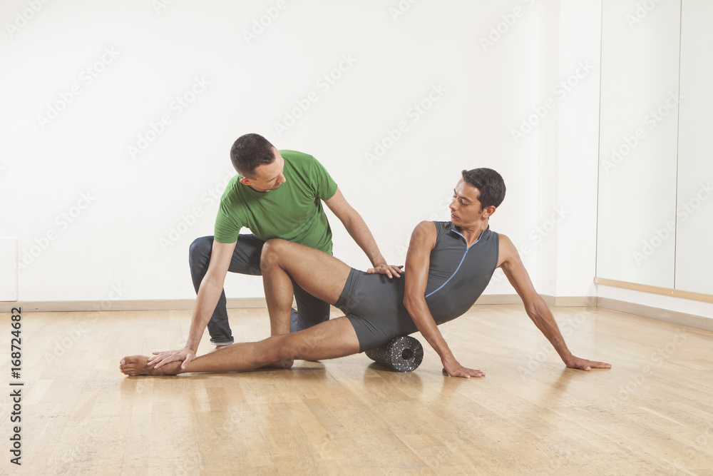 Obraz premium pilates instructor teaching a ballet dancer using foam roller