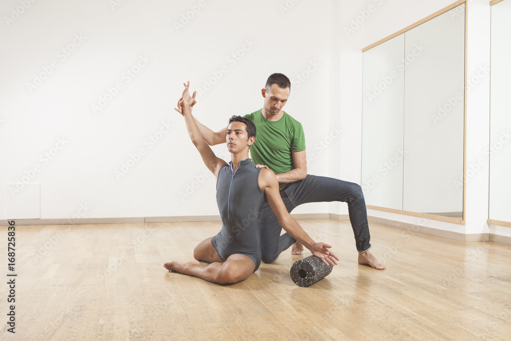 Fototapeta premium pilates instructor teaching a ballet dancer using foam roller