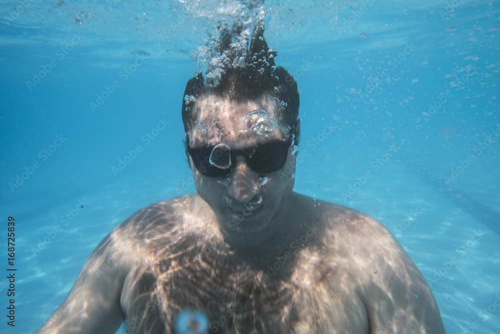 Naklejka premium cool man underwater with sunglasses looking at camera