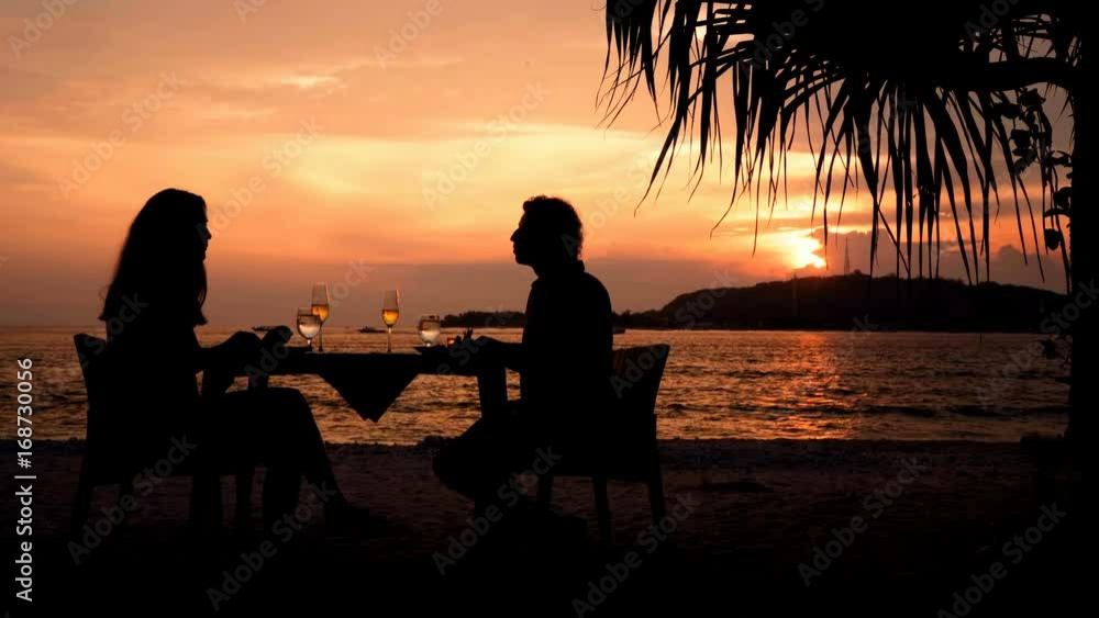 Couple silhouettess having romantic dinner on beach at sunset. Shot with Sony a7s and Atomos Ninja Flame in Gili Meno, Indonesia.