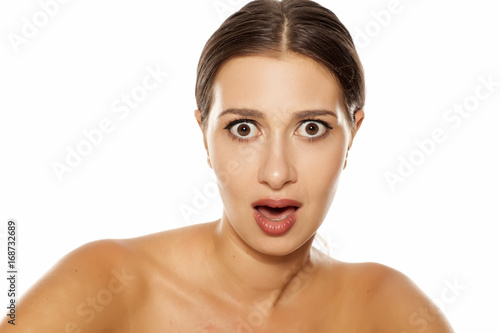 An unpleasant surprise of a young woman on a white background