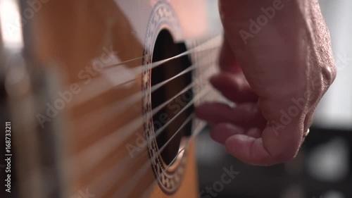 Musician plays acoustic spanish guitar. Close up shot of right hand, shallow depth of field