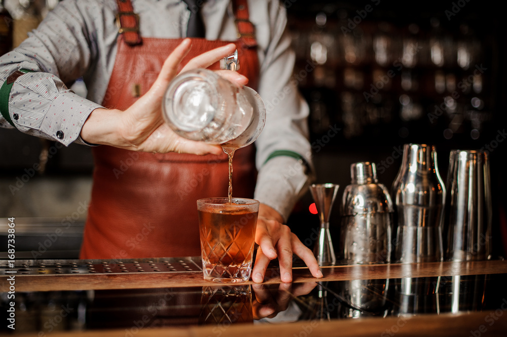 Barman in bar interior making alcohol cocktail. No face