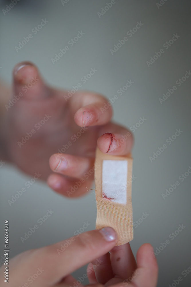 parent applying band aid on finger wound. hands, cut, blood, bandage. Stock  Photo