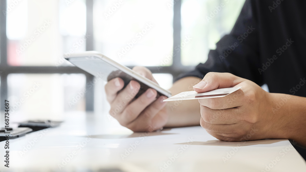 credit card on hand a man using smartphone for shopping online. credit card on hand a man using smartphone for shopping online.