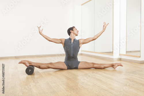 professional ballet dancer stretching and warming up using foam roller