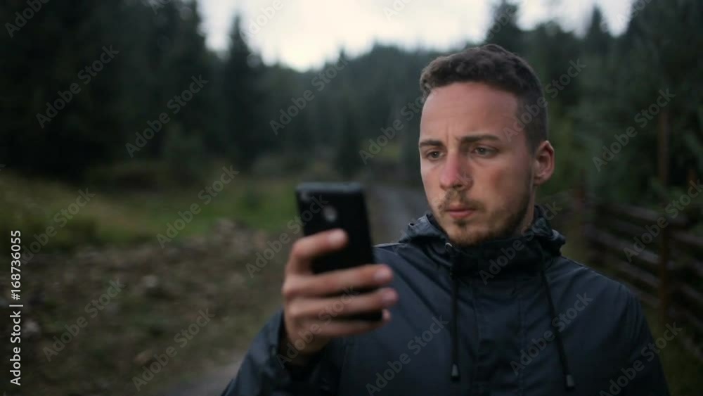 A young man writes an SMS in the evening in the mountains. Around the forest in the fog A young man writes an SMS in the evening in the mountains. Around the forest in the fog
