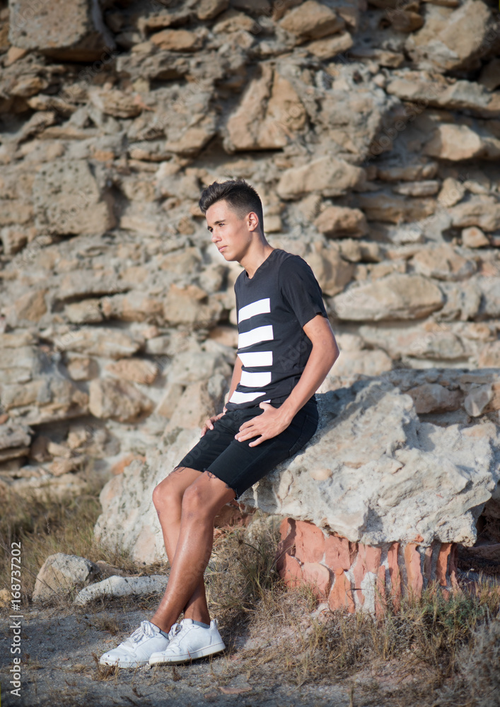 handsome guy sits on the rocks handsome guy sits on the rocks
