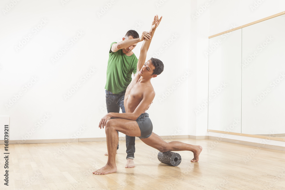 pilates instructor teaching a ballet dancer using foam roller