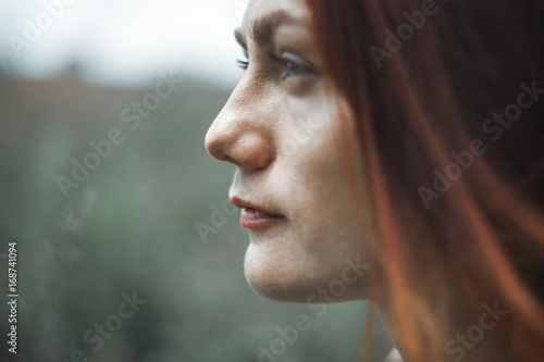 Portrait of a beautiful red-haired girl on a background of nature