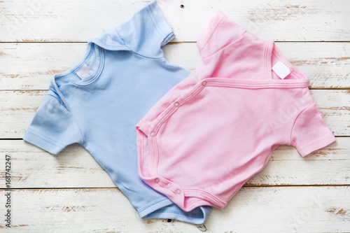 Foto Pink and blue baby romper on white wooden background