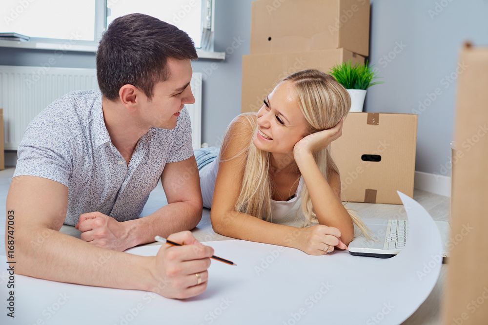 A happy couple is drawing a plan on the floor in a new apartment at home. A happy couple is drawing a plan on the floor in a new apartment at home.