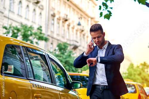 Young businessman talking on a phone and waiting for his taxi