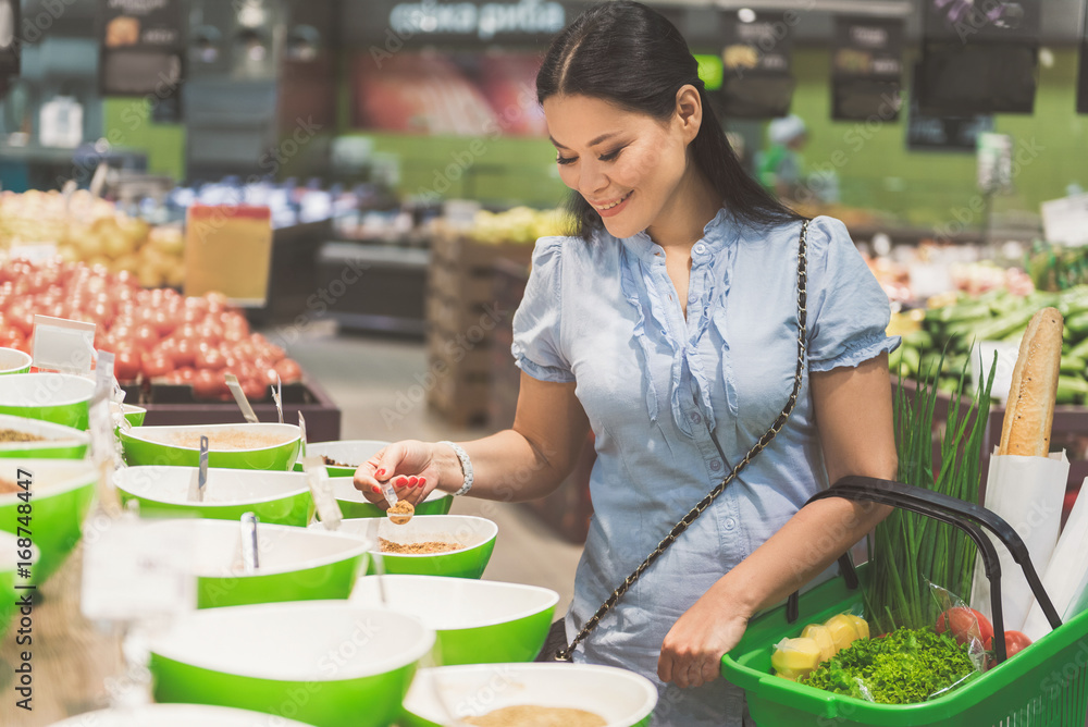 Outgoing woman choosing vegetable herb in shop