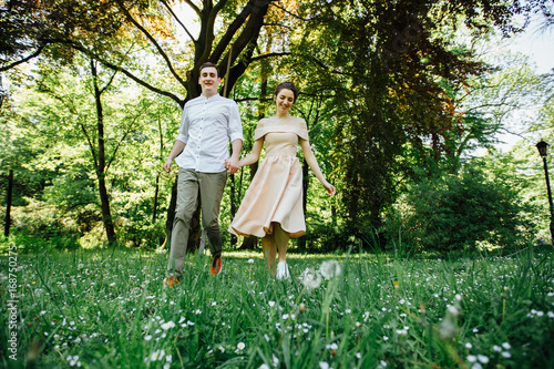 Dinamic photo of beautiful wedding couple holding by hands, running and laughing in sunny day. Love, wedding day and celebration concept.