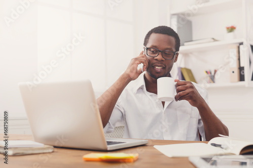 Young black businessman call mobile phone in modern white office