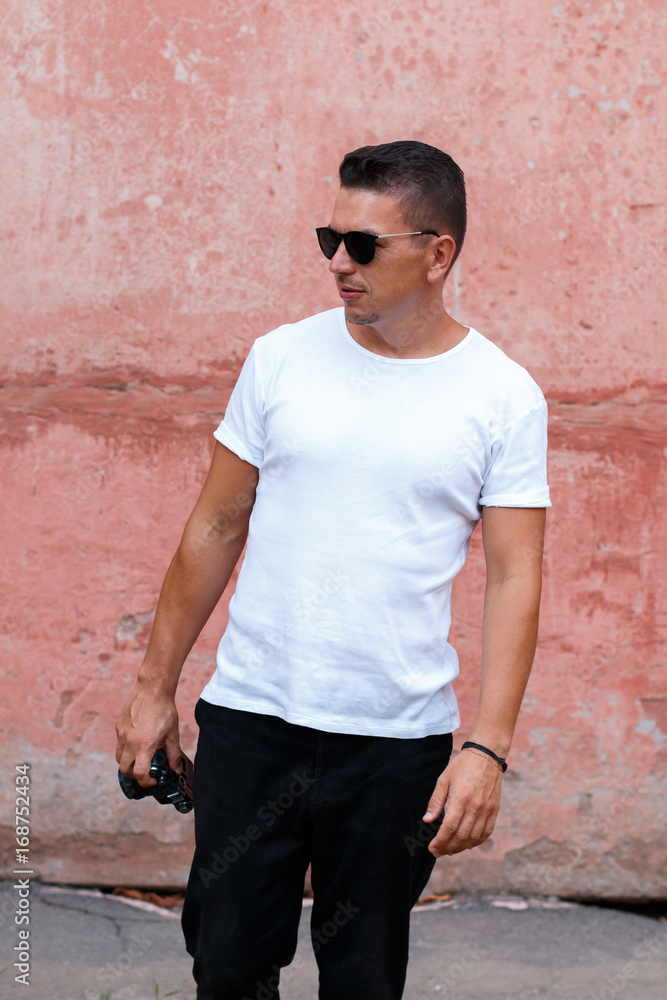 Guy with retro camera in white shirt in front of pink wall background Guy with retro camera in white shirt in front of pink wall background