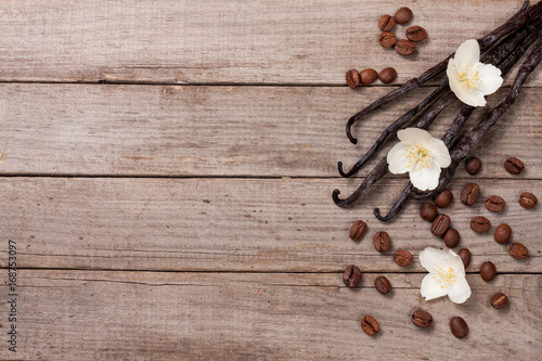 Vanilla sticks with coffee beans avd flower on a old wooden background with copy space for your text. Top view