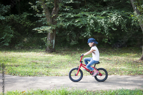 Fototapeta Naklejka Na Ścianę i Meble -  Little girl playing with red bicycle