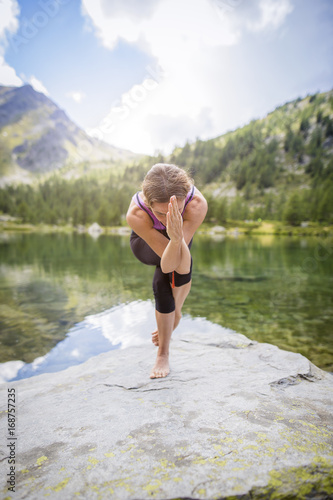 Ragazza che pratica yoga all'aperto sul lago