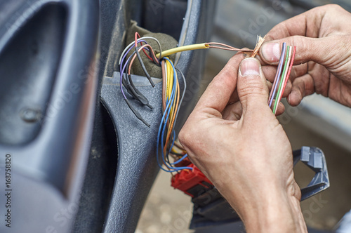  Mechanic's hands repairing electrical wires in the door of old car 