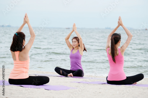 Group of young healthy people practicing yoga on the beach, healthy lifestyles, wellness, well being