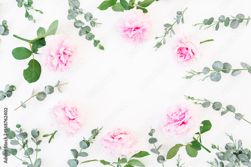 Floral round frame of pink roses and eucalyptus branches on white background. Flat lay, top view