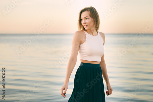 a woman in a the skirt and top is walking along the beach photo