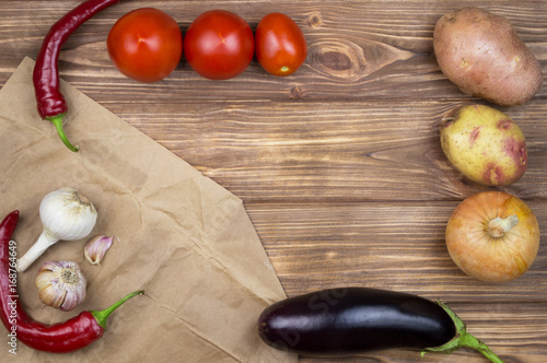 Vegetables on a wooden background. Potatoes, tomatoes, garlic, onions, basil, eggplant