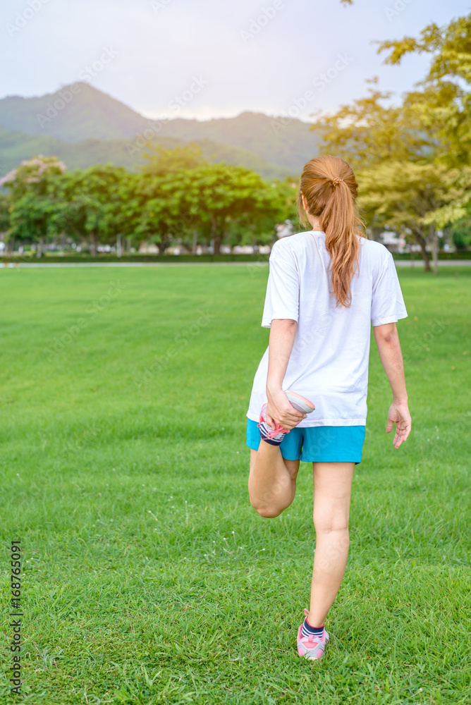Woman exercise outdoors in park in sunrise morning with mountain in background