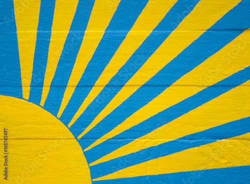 Sunburst in yellow and blue on wood panel background