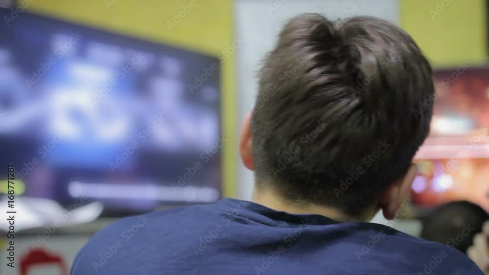 Young male choosing video game, looking at TV screen, leisure time and hobby Young male choosing video game, looking at TV screen, leisure time and hobby