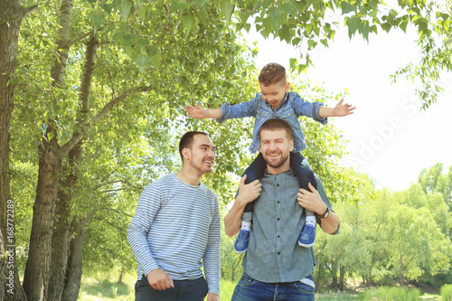 Smiling gay couple with son...