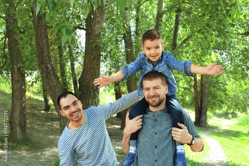 Smiling gay couple with son...