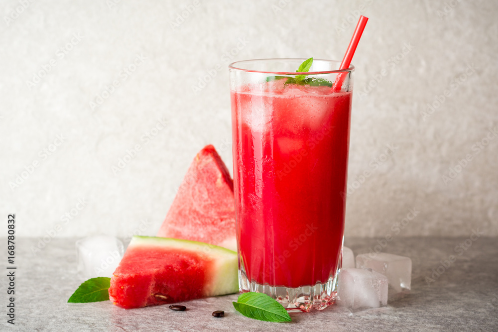 Fresh watermelon smoothie with ice and mint in glass on gray stone background Fresh watermelon smoothie with ice and mint in glass on gray stone background