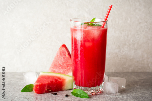 Fresh watermelon smoothie with ice and mint in glass on gray stone background